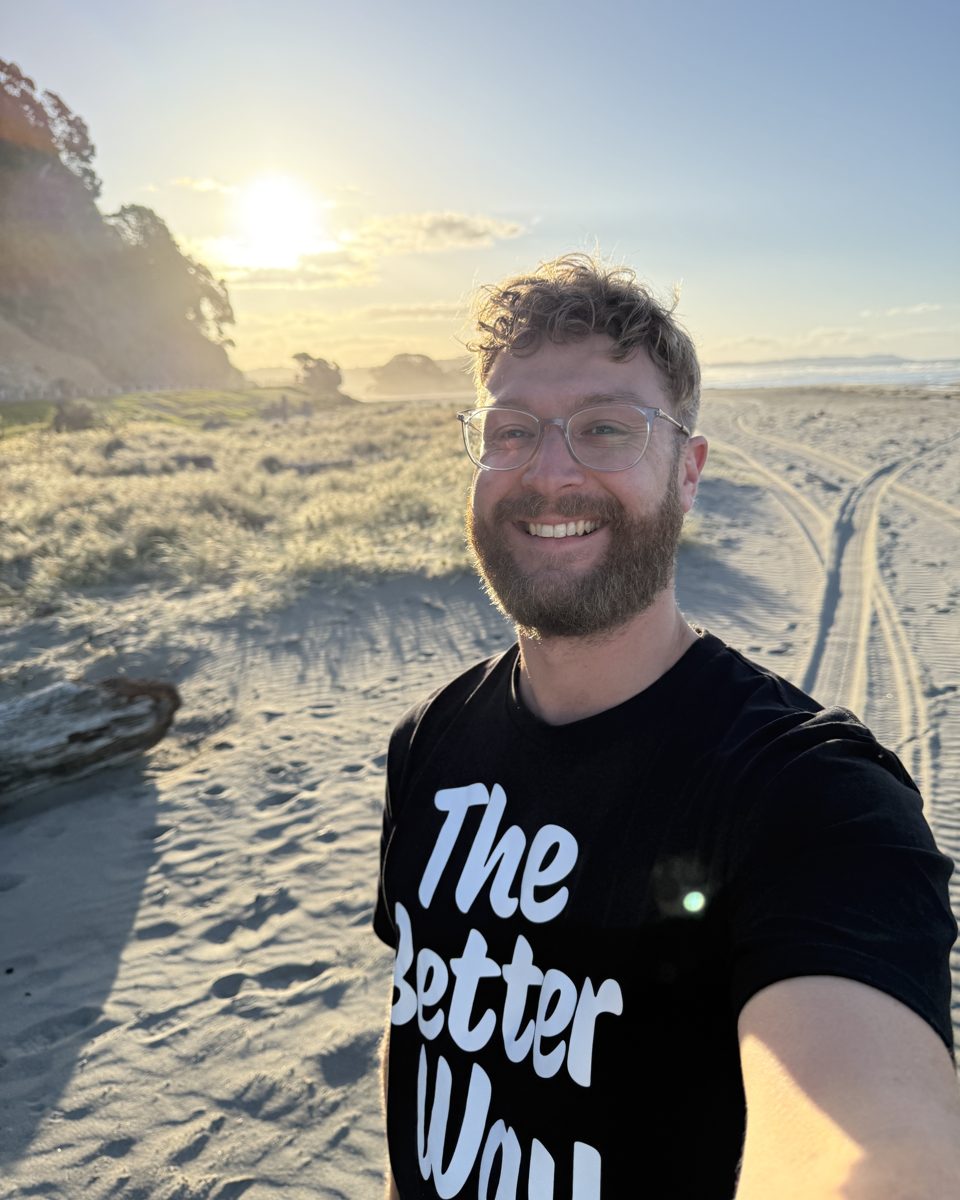 Damian Redpath, founder of Better Digital, smiling on a New Zealand beach at sunset
